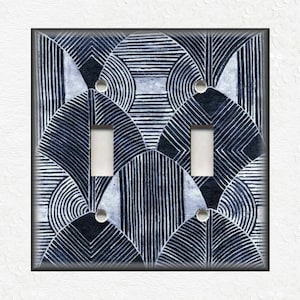 May include: A double light switch cover with a black and white geometric pattern. The pattern features overlapping circles and lines.