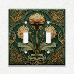 May include: Decorative double light switch cover with a floral design. The cover features a teal background with gold and beige floral accents. The design includes two large flowers and ornate leaf details.