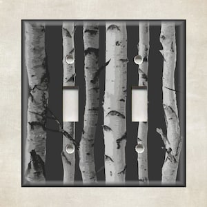 May include: A black and white light switch cover with a pattern of birch trees. The switch cover has two toggle switches.