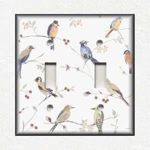 May include: A white light switch cover with a watercolor design of birds on branches. The birds are blue, brown, and yellow. The branches are white and have small red berries.
