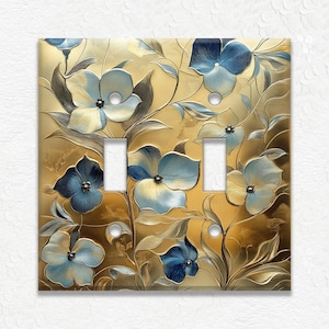 May include: A decorative double light switch cover featuring a floral design. The cover has a gold background with blue and cream-colored flowers and leaves. The flowers have a textured, three-dimensional appearance.