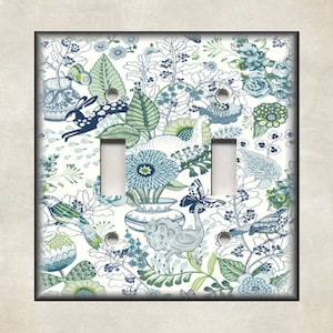 May include: A white light switch cover with a blue and green floral pattern. The pattern features birds, butterflies, and rabbits.