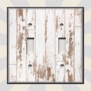 May include: White and brown woodgrain light switch cover plate. The cover plate has a distressed look with white paint over brown wood.