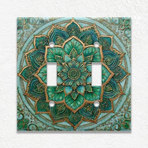 May include: A decorative light switch cover featuring a teal and gold mandala design. The intricate floral pattern is embossed with a raised texture. The cover has two switch openings and four screw holes.