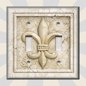 May include: A light switch cover with a decorative fleur-de-lis design on a faux marble background.
