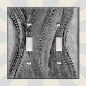 May include: A light gray and white double light switch cover with a wavy abstract design.