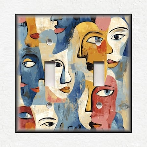 May include: Abstract art light switch cover featuring a colorful collage of faces with blue, yellow, red, and white paint.