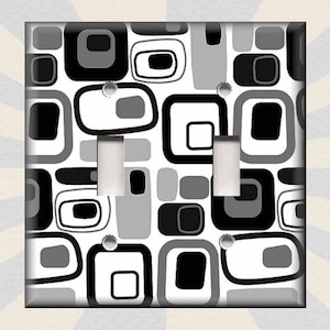 May include: A white light switch cover with a black and gray geometric pattern. The pattern is made up of squares, rectangles, and circles.