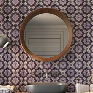 May include: A bathroom vanity with a round wooden mirror, a white porcelain sink, and a gray tiled wall with a geometric pattern. The vanity is decorated with a small potted plant and a decorative soap dispenser.