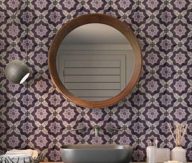 May include: A bathroom vanity with a round wooden mirror, a white porcelain sink, and a gray tiled wall with a geometric pattern. The vanity is decorated with a small potted plant and a decorative soap dispenser.