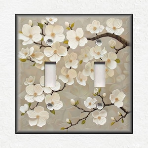 May include: A double light switch cover with a floral design. The cover features white flowers with a light brown background.