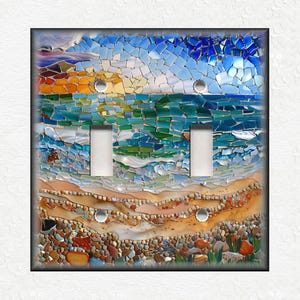May include: A mosaic light switch cover featuring a beach scene with a sunset, ocean waves, and a sandy shore with pebbles. The mosaic is made of small, colorful glass tiles.