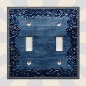 May include: A blue double light switch cover with a wood grain texture and a decorative border of swirling floral designs.
