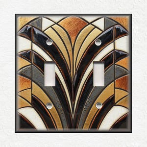 May include: A double light switch cover with a geometric design in shades of brown, black, gold, and white. The design features a repeating pattern of curved lines and shapes.