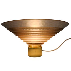 May include: A gold-toned table lamp with a layered, frosted glass shade. The shade has a scalloped edge and a white cord.