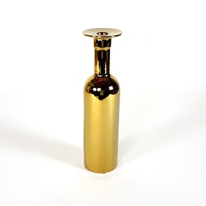 Puede incluir: Un jarrón de cerámica dorado con una parte superior ancha y plana. El jarrón tiene forma de botella y tiene un acabado metálico brillante.
