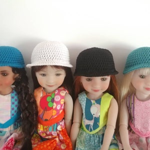 May include: Four dolls wearing different colored crocheted hats. The hats are all the same style, with a flat brim and a rounded crown. The dolls are wearing colorful dresses.