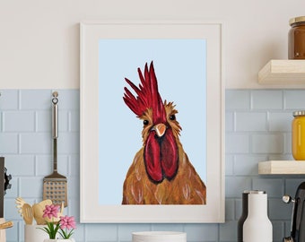 May include: A framed watercolor painting of a rooster with a red comb and wattle against a light blue background. The rooster's feathers are shades of brown and gold. The artwork is displayed in a white frame.
