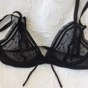 May include: Black lace lingerie bra with a delicate polka dot pattern and adjustable straps.