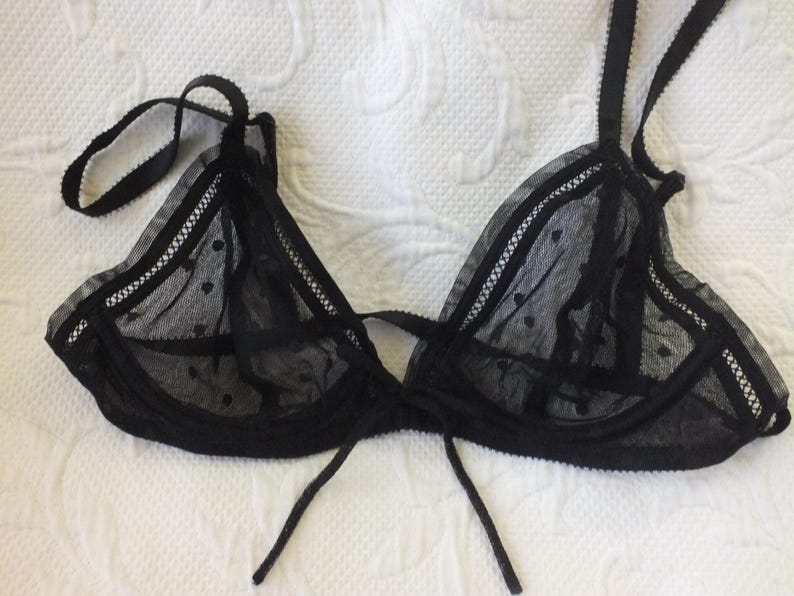 May include: Black lace lingerie bra with a delicate polka dot pattern and adjustable straps.