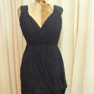 May include: A dark blue, sleeveless dress with a draped, flowing design. The dress has a V-neckline and a gathered waist.