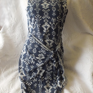 May include: Sleeveless navy blue dress with a white damask pattern. The dress features a knotted waist detail and a scoop neckline. The fabric has a soft drape, and the dress is displayed on a mannequin.