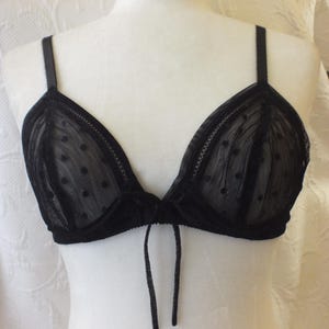 May include: Black lace bra with polka dots and a tie detail in the front.