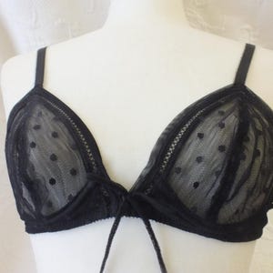 May include: Black lace bra with polka dots. The bra has adjustable straps and a tie closure in the front.