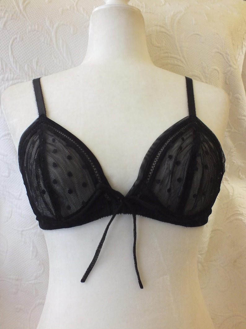 May include: Black lace bra with polka dots and a tie detail in the front.