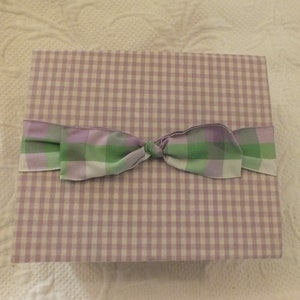 May include: A lavender and green gingham gift box with a matching ribbon tied in a bow.