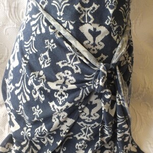 May include: A navy blue wrap dress with a white floral pattern. The dress is tied at the waist with a matching fabric belt. The fabric is soft and flowing, perfect for a summer day.