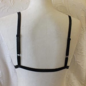 May include: Black lingerie bra with adjustable straps. The bra has a simple design with a thin band and straps.