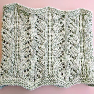 May include: A light green knitted scarf with a lacy pattern. The scarf is made with a soft yarn and has a delicate, feminine look.