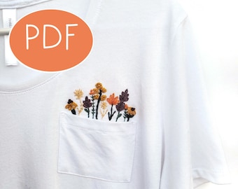 May include: White t-shirt with a pocket featuring embroidered flowers in shades of orange, yellow, brown, and purple. The text "PDF" is visible in the top left corner of the image.