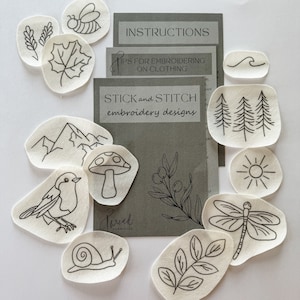 Puede incluir: Un conjunto de diseños de bordado con motivos inspirados en la naturaleza, como una abeja, una hoja y montañas. Los diseños están en pequeños parches de tela ovalados. Se incluyen instrucciones y un folleto titulado "Stick and Stitch embroidery designs."
