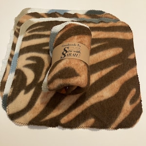 May include: A stack of brown, tan, and white fleece cloths with a brown and tan swirl pattern. The cloths are rolled up and tied with a brown paper tag that says "Handmade By Sew with SARAH!"