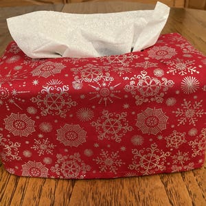 May include: Red tissue box cover with a white snowflake pattern.