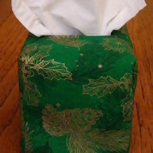 May include: A green tissue box cover with a gold leaf and holly design.