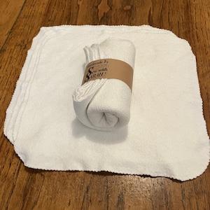 May include: A set of white, soft, cotton dishcloths with a scalloped edge. The cloths are rolled up and tied with a brown paper tag that reads "Handmade by Sew with SARAH!"