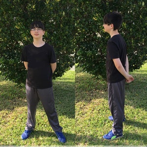 May include: A boy wearing a black t-shirt and gray sweatpants stands in front of a green bush. The text "CASUAL PANTS / SHORTS PATTERN" is at the bottom of the image.
