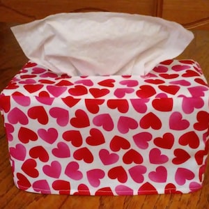 May include: A white tissue box cover with a pink and red heart pattern.