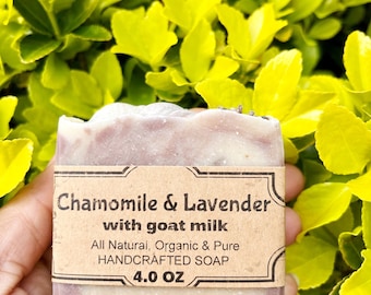 May include: A bar of handmade soap with a label that reads "Chamomile & Lavender with goat milk". The soap is a light pink and white color and has a swirl pattern. The label also says "All Natural, Organic & Pure HANDCRAFTED SOAP 4.0 OZ".