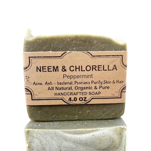 May include: Two bars of green handmade soap with a brown label that reads "NEEM & CHLORELLA Peppermint Acne, Anti-bacterial, Psoriasis Purify Skin & Hair All Natural, Organic & Pure HANDCRAFTED SOAP 4.0 OZ"