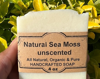 May include: A white bar of soap with a brown label that reads "Natural Sea Moss unscented All Natural, Organic & Pure HANDCRAFTED SOAP 4 oz".