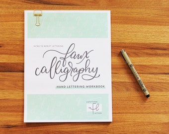 May include: A white workbook with a green background and the text "Intro to Script Lettering: Faux Calligraphy Hand Lettering Workbook" and a logo that says "Unfettered Letters".