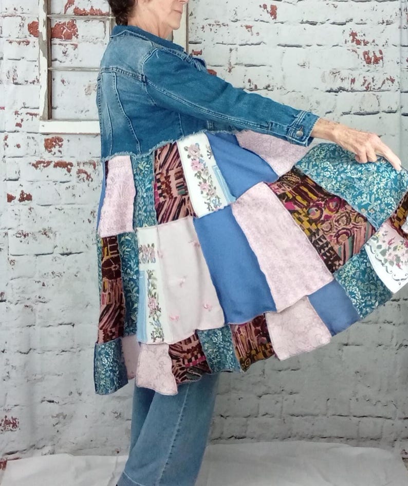 Blue denim coat with three tiers of fabric added to the bottom. Pinks, blues and brown fabrics on bottom. Hits past the knees.