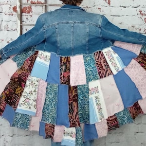 Blue denim coat with three tiers of fabric added to the bottom. Pinks, blues and brown fabrics on bottom. Hits past the knees.