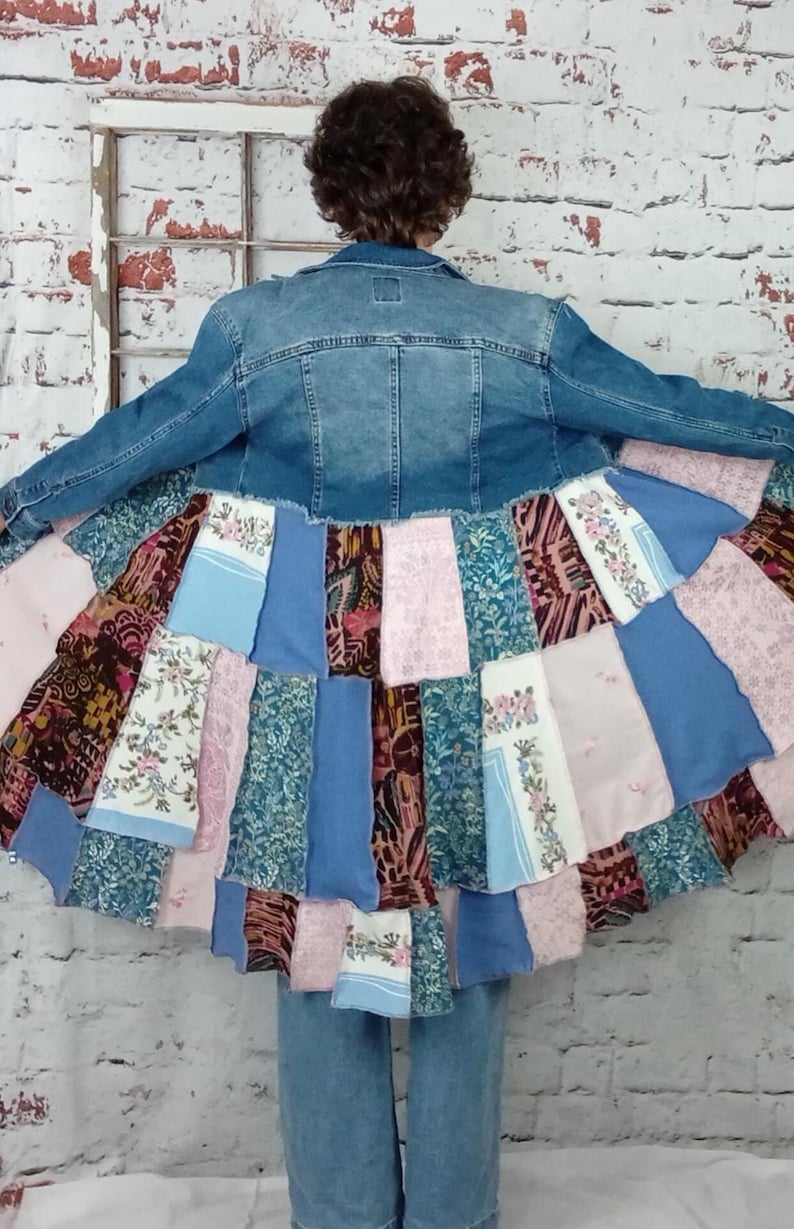 Blue denim coat with three tiers of fabric added to the bottom. Pinks, blues and brown fabrics on bottom. Hits past the knees.