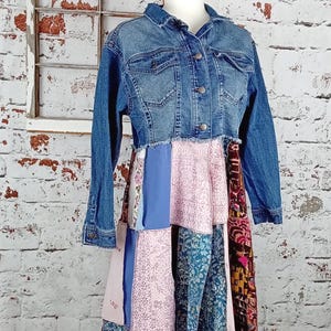Blue denim coat with three tiers of fabric added to the bottom. Pinks, blues and brown fabrics on bottom. Hits past the knees.