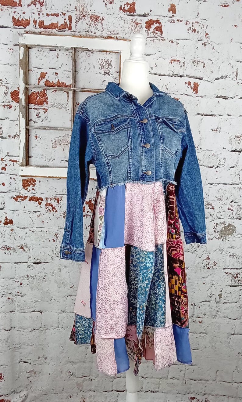 Blue denim coat with three tiers of fabric added to the bottom. Pinks, blues and brown fabrics on bottom. Hits past the knees.